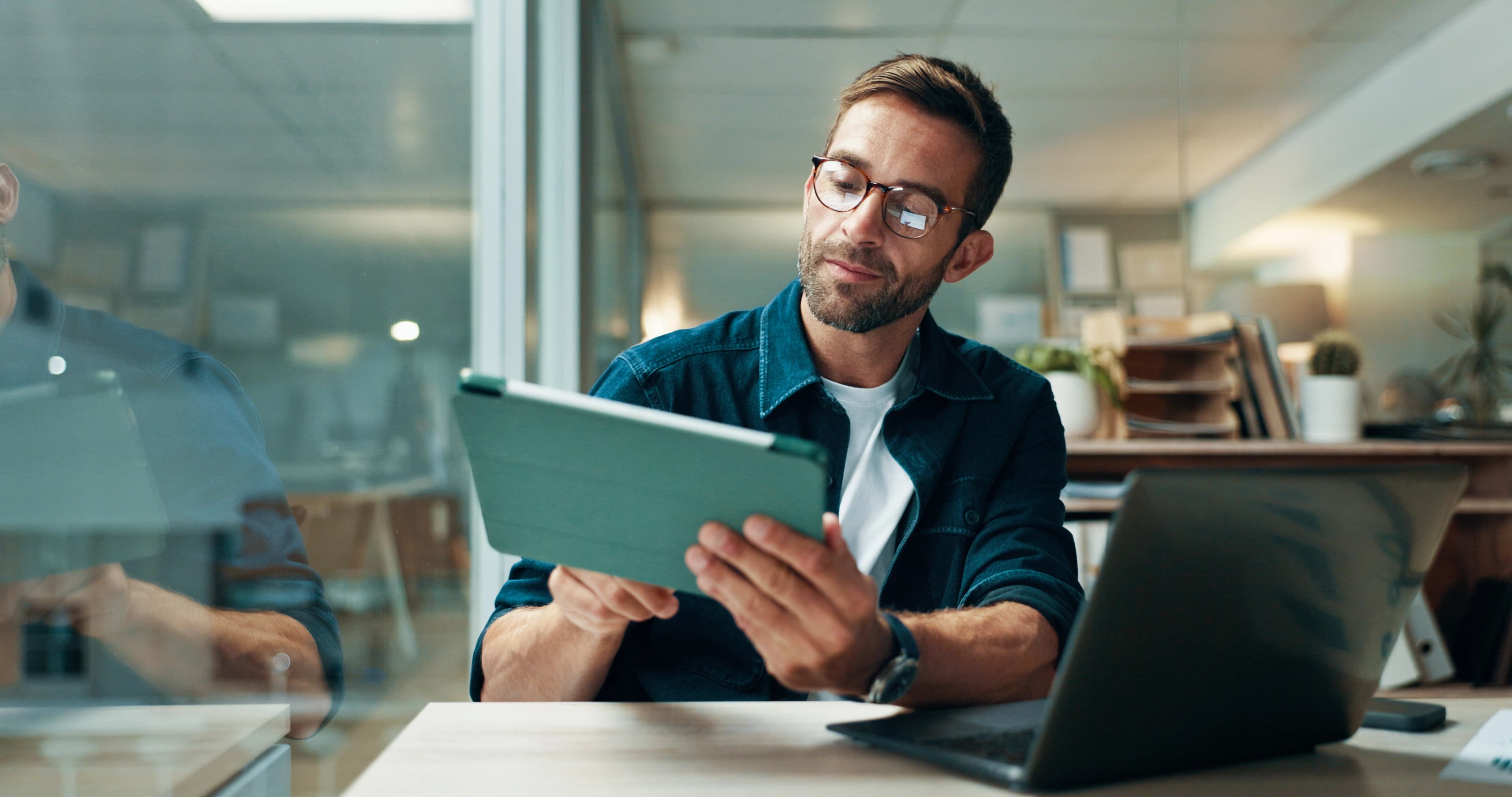 man holding a tablet at a desk