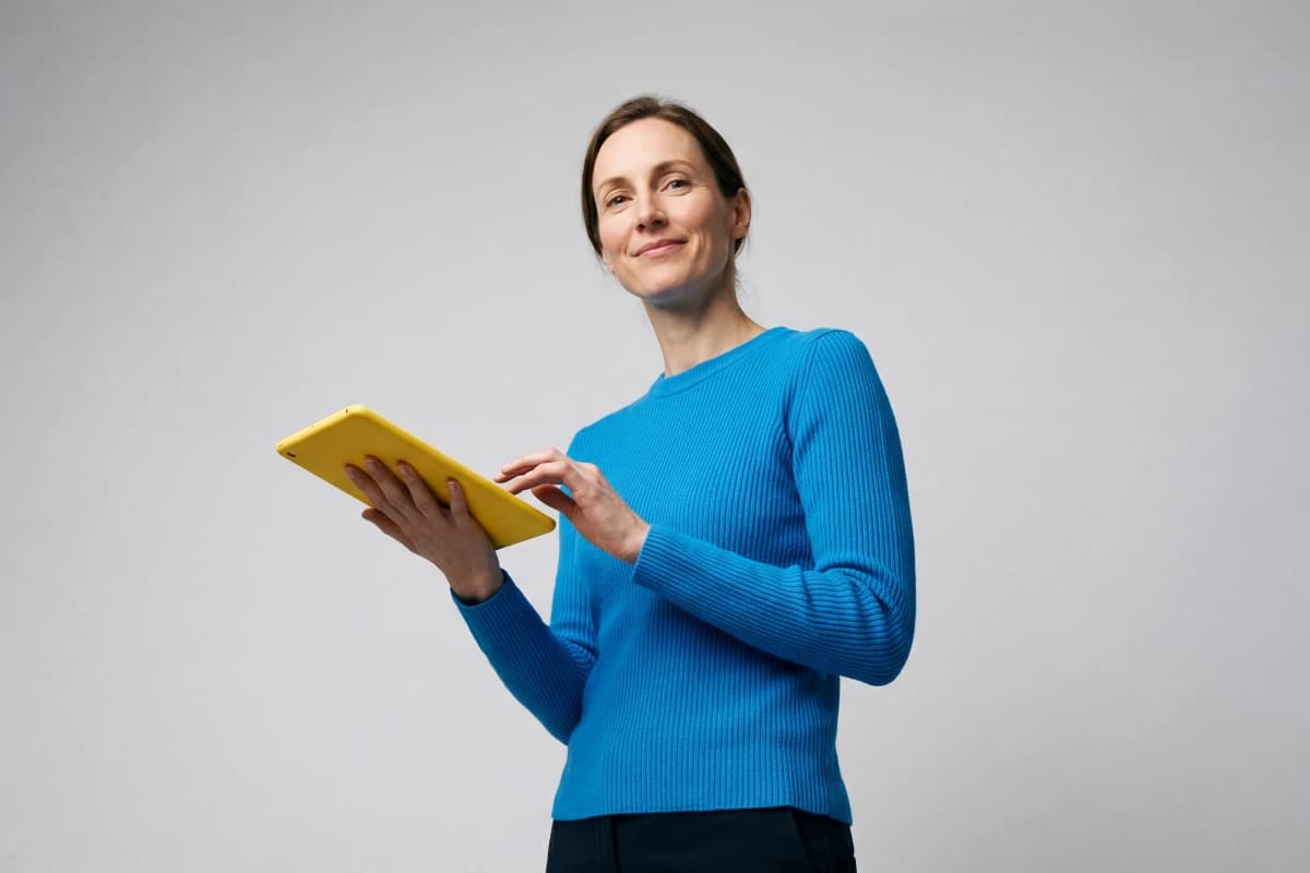 woman holding a yellow tablet on a grey background