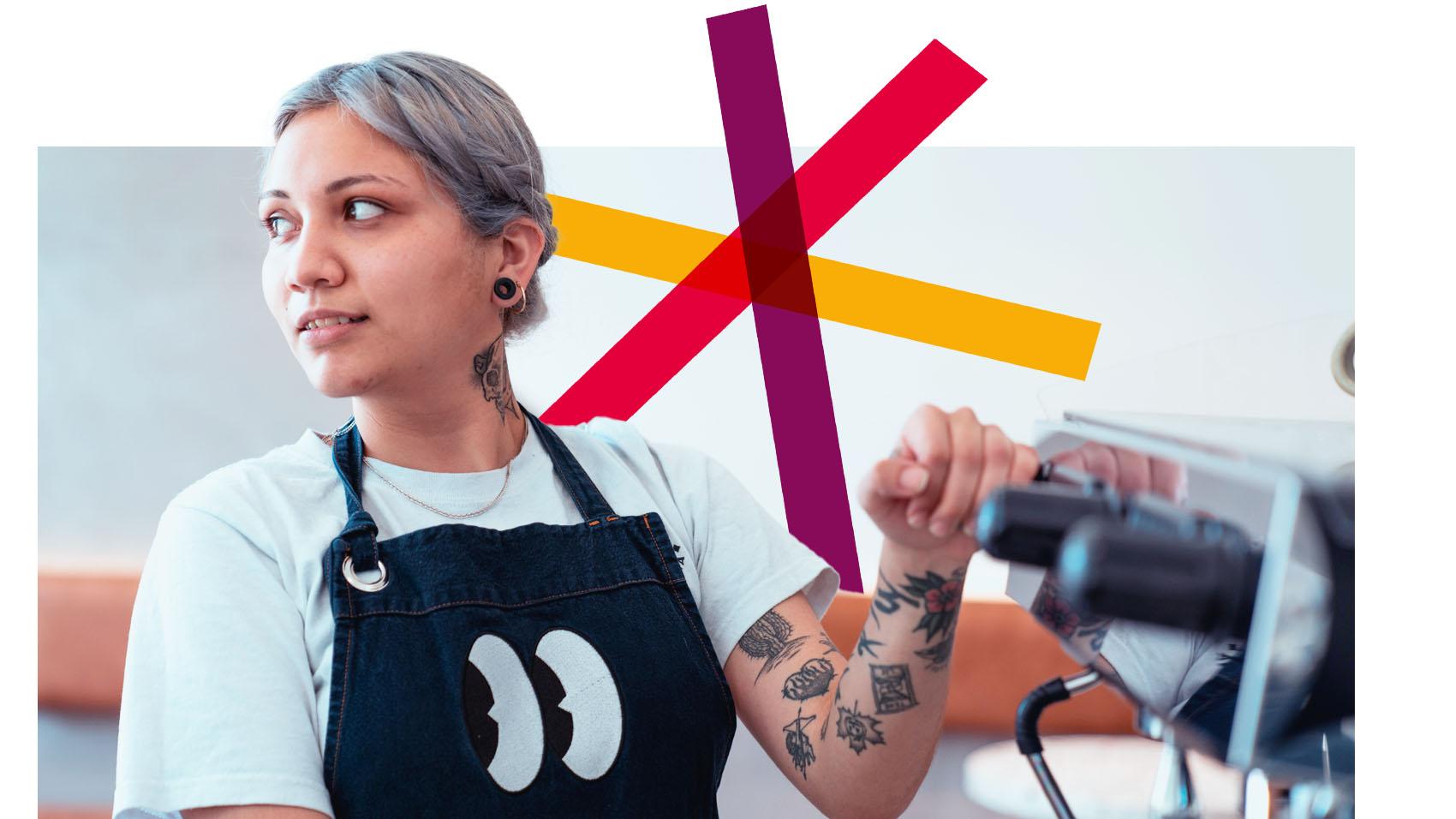 A woman with tattoos is using a coffee machine in a cafe 